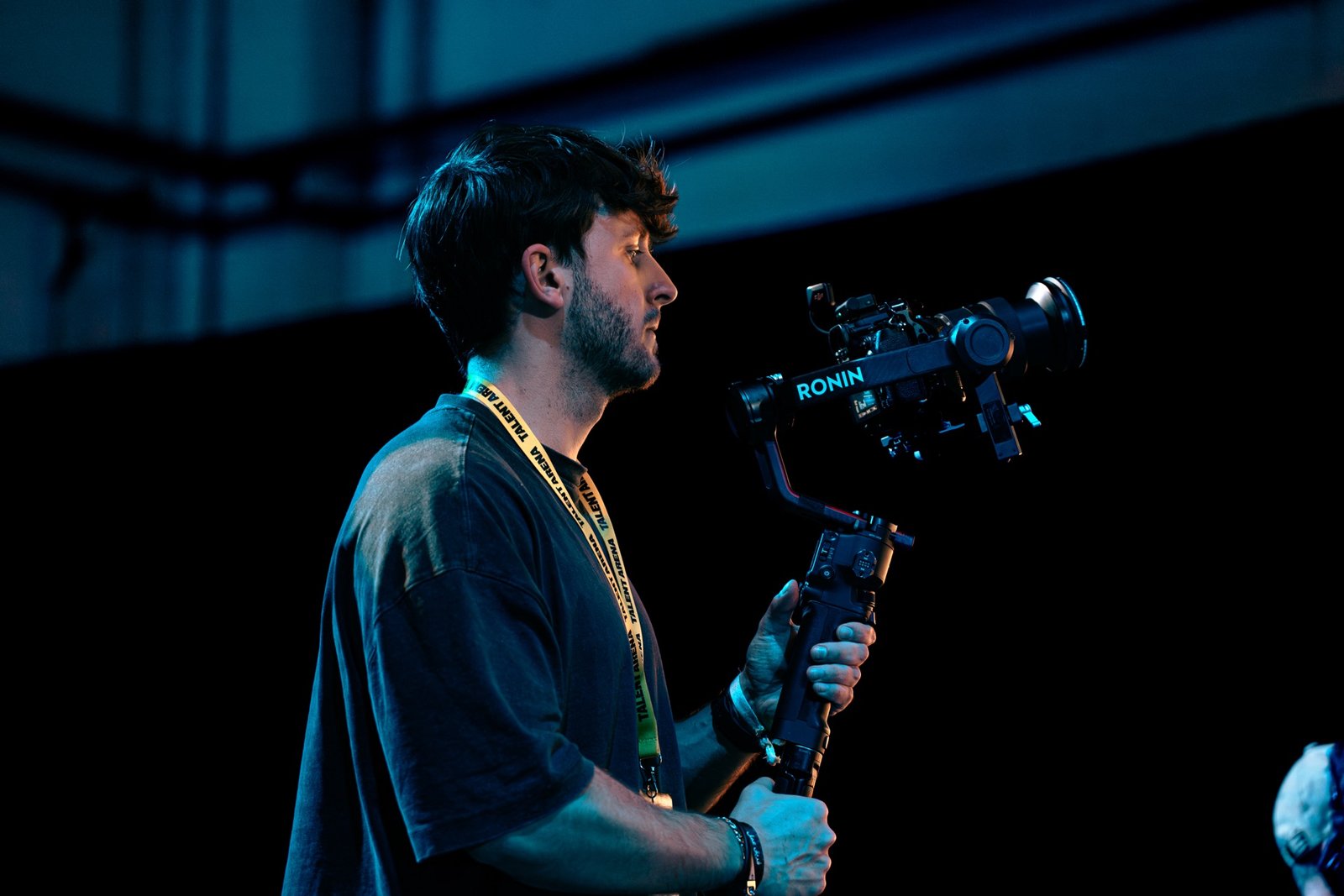 Jan Castany de perfil, grabando con una cámara sobre gimbal en un escenario iluminado en azul.